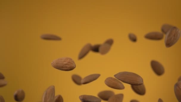 Tutup almond terbang dan berputar pada latar belakang kuning — Stok Video