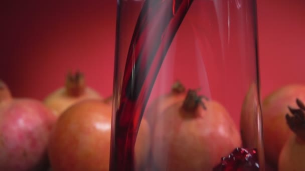 Delizioso succo di melograno rosso viene versato in una brocca sullo sfondo rosso — Video Stock