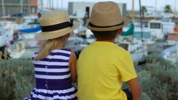 Ragazzino e ragazza sono seduti e guardando sul molo del porto yacht — Video Stock