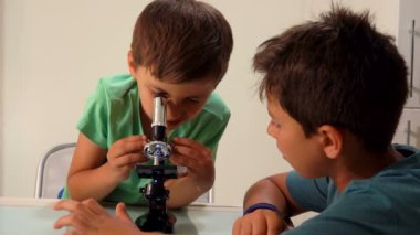 İki bronzlaşmış kardeş mikroskoptan ciddi şekilde bakıyor.
