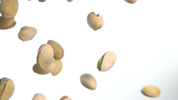 Primer plano de pistachos asados volando diagonalmente sobre fondo blanco — Vídeos de Stock