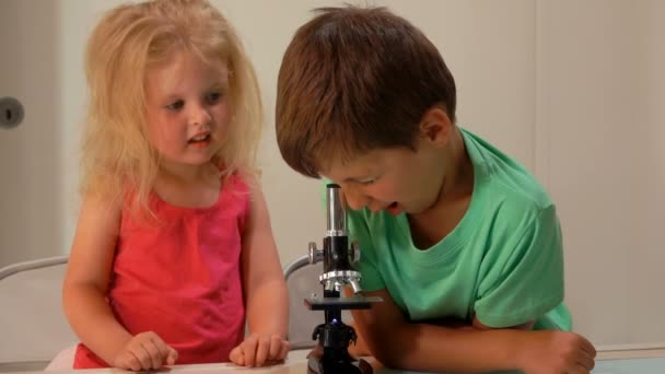 Μικρό αγόρι και χαριτωμένο κοριτσάκι είναι κατάπληκτοι από την εικόνα σε ένα φακό μικροσκόπιο — Αρχείο Βίντεο