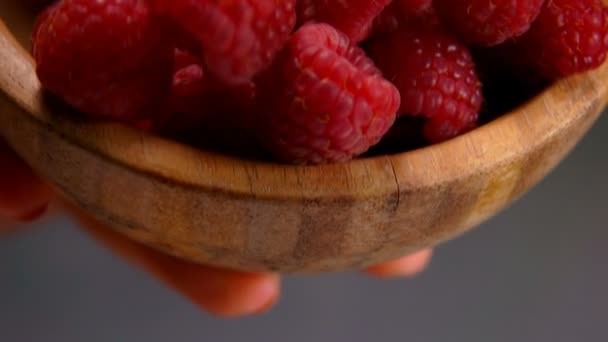 Крупный план большой сочной аппетитной малины, падающей с деревянной чаши — стоковое видео