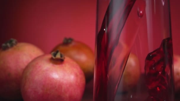 Detailní záběr granátové šťávy proudící do džbánu na červeném pozadí — Stock video