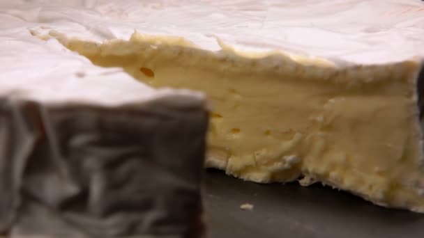 Close-up de um delicioso pedaço de queijo brie macio retirado da superfície preta — Vídeo de Stock