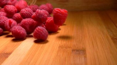 Hasır sepetten ahşap masaya düşen büyük sulu ahududular.