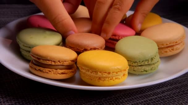 Muitas mãos tomam macaroons de amêndoa francesa da placa branca — Vídeo de Stock