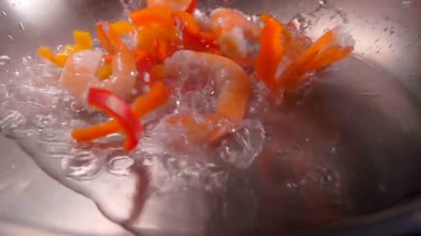 Close-up de grandes camarões e pimenta vermelha caindo em um óleo quente — Vídeo de Stock