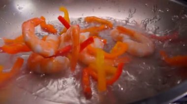 Büyük karidesler ve kırmızı biber tavaya dökülür.