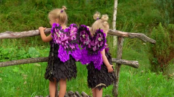 Las niñas con alas de mariposa están de pie en el puente de madera al aire libre — Vídeo de stock