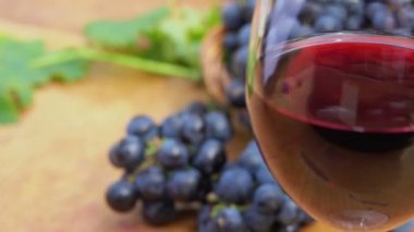 Koyu mor üzümlerin arka planında şarap kadehini kapat.