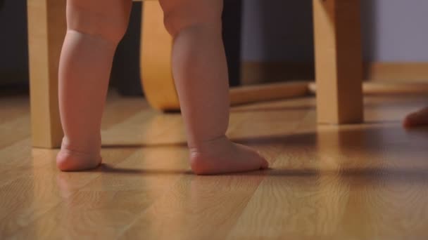 椅子の横にあるつま先に立っている小さな愛らしい赤ちゃんの低角度ビュー — ストック動画