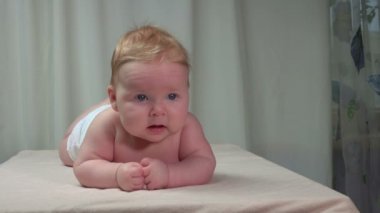 Küçük şirin bebek battaniyenin üzerine uzanmış ve kameraya bakıyor.