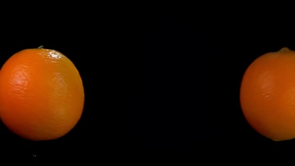 Zwei Orangen fliegen und kollidieren miteinander steigende Wasserspritzer — Stockvideo