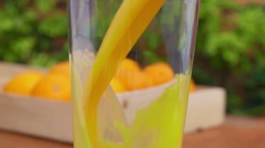 Lezzetli portakal suyu olgun portakallarla dolu bir kutunun yanına dökülür.