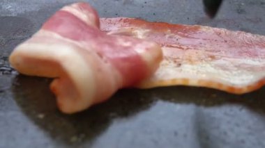 Düz ızgara taş yüzeyinde kavrulmuş domuz pastırması şeritleri.