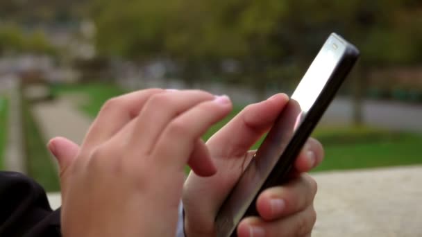 Primer plano de un dedo de un escolar haciendo clic en la pantalla del teléfono al aire libre — Vídeo de stock