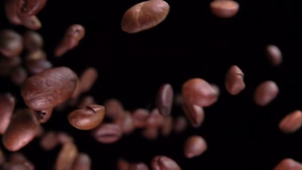 Gros plan des grains de café torréfiés volant en diagonale sur le fond noir — Video