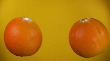 Sarı arka planda iki portakal çarpışıyor.