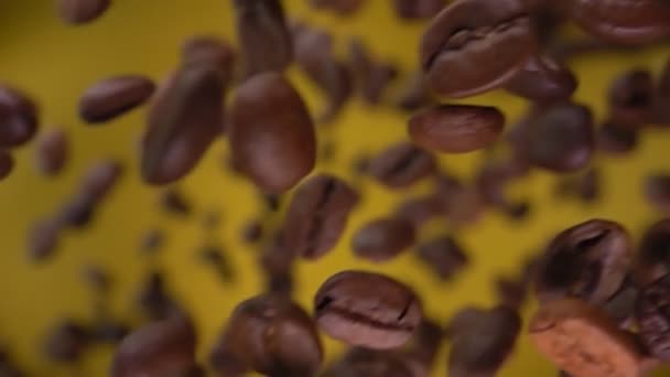 Detailní pohled na pražená kávová zrna létající na okrově žlutém pozadí — Stock video