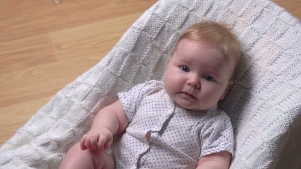Klein schattig mollig baby op een witte deken is op zoek naar handen — Stockvideo