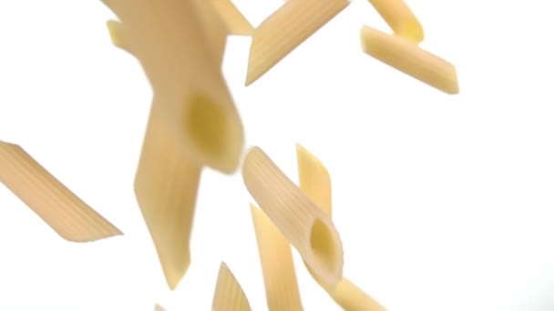 Torr rå pasta penne flyger diagonalt på en vit bakgrund — Stockvideo