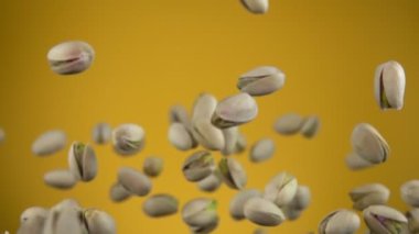 Sarı arka planda uçan ve dönen şam fıstıklarını kapat