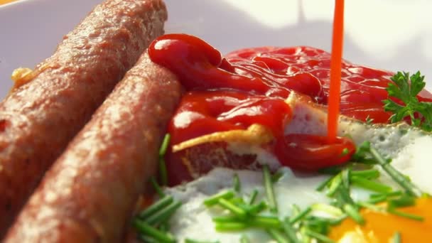 Ketchup hälls på den vita tallriken bredvid stekt korv och ägg — Stockvideo