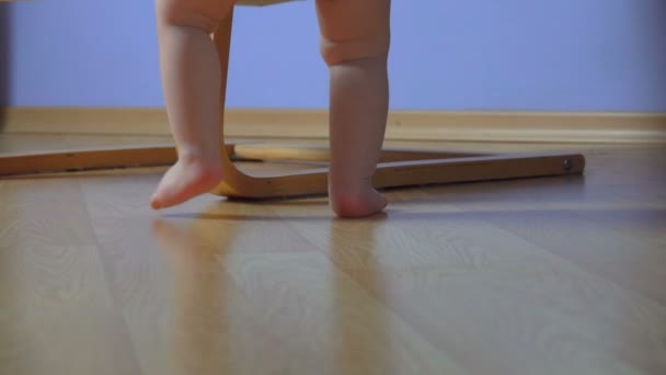 Low-angle view of a chubby feet of little baby trying to get on the chair — Stock Video