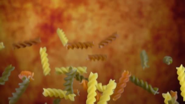 Fusili di pasta cruda colorati che rimbalzano su uno sfondo giallo ocra — Video Stock