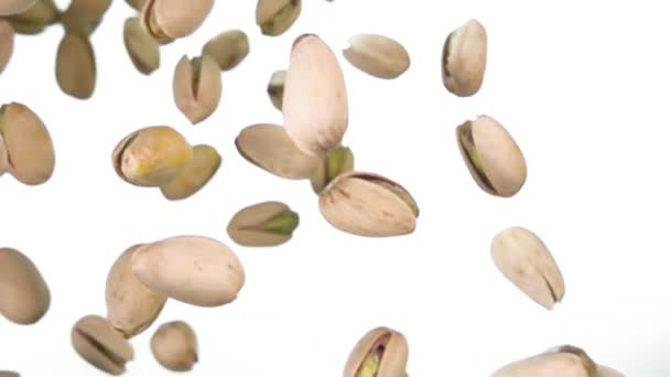 Gros plan de pistaches grillées tombant et tournant sur fond blanc — Video
