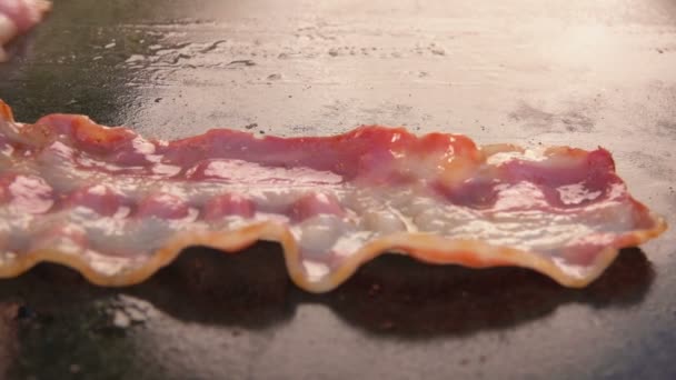 Närbild av läckra remsor av bacon rostning av platt grill — Stockvideo