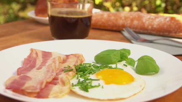 Крупный план белой тарелки с жареным беконом и яйцами — стоковое видео
