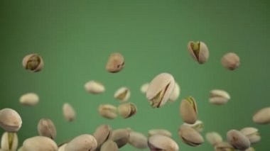 Zeytin yeşili arka planda uçuşan tuzlu şam fıstıklarını kapatın.