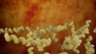 Çiğ makarna selentanisi yukarı doğru uçuyor ve sarı bir zemin üzerine düşüyor.