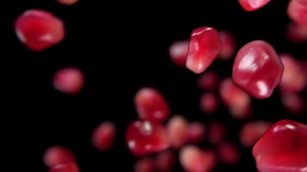 Šťavnatá zrnka zralého granátového jablka padají diagonálně na černé pozadí — Stock video