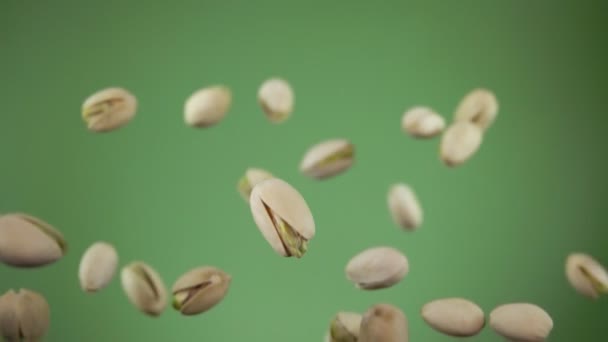 Close up de pistácios saltando e girando sobre o fundo verde — Vídeo de Stock