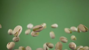 Zeytin yeşili arka planda zıplayan tuzlu şam fıstıklarını kapat.