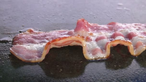 Primer plano de deliciosa tira de tocino frito tostado en la superficie plana de la parrilla — Vídeos de Stock