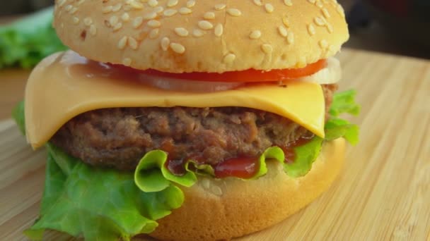 Panorama de la rotonda de una deliciosa hamburguesa casera con queso en el tablero de madera — Vídeo de stock
