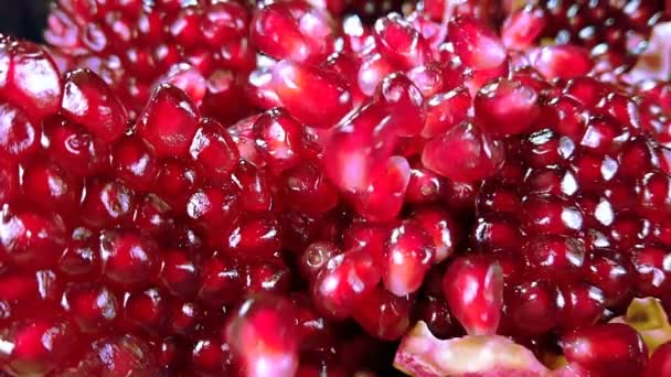 Red grains of ripe pomegranate are falling on the surface of broken pomegranate — Stock Video