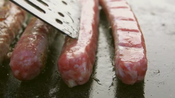 Deliziose salsicce stanno friggendo sulla griglia di pietra — Video Stock