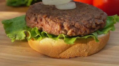 Eldivenli eller hamburgerin üzerine taze soğan halkaları seriyor.