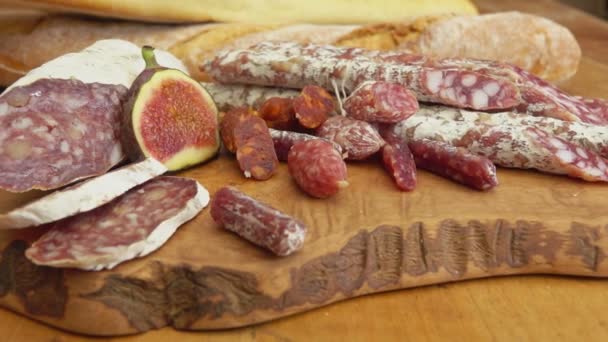 Panorama of delicious dry sausages laying on a wooden board with figs — Stock Video