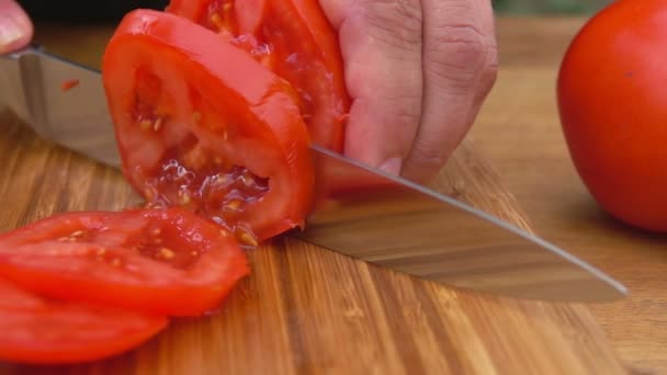 Gros plan des mains coupant une tomate rouge juteuse en tranches — Video