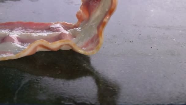 Närbild av läckra stekt bacon remsa om till platt grill yta — Stockvideo