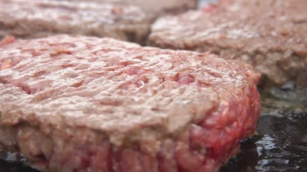 Zbliżenie pysznych kotletów wołowych do smażenia burgerów na płaskiej powierzchni grilla — Wideo stockowe