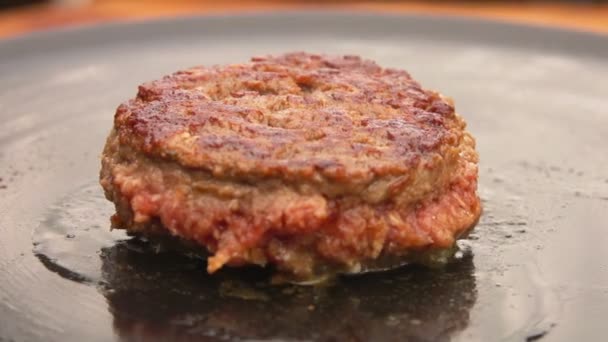 Close-up of juicy beef cutlet for a burger frying on the flat grill outdoors — Stock Video