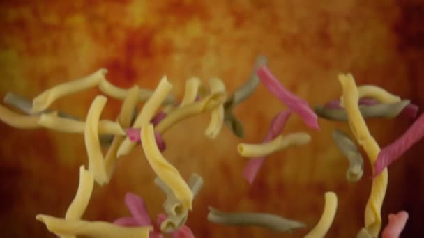 Gekleurde pasta casarecce vliegt omhoog en draait op een gele oker achtergrond — Stockvideo
