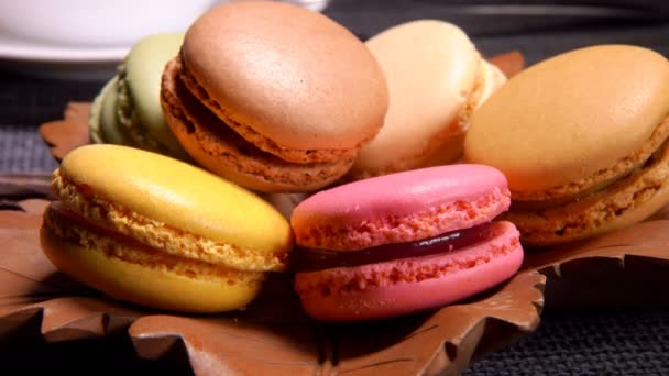 Macaroons de amêndoa franceses multicoloridos em uma placa marrom em forma de folha — Vídeo de Stock